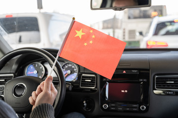 Middle aged man with Chinese flag driving a car.  China .