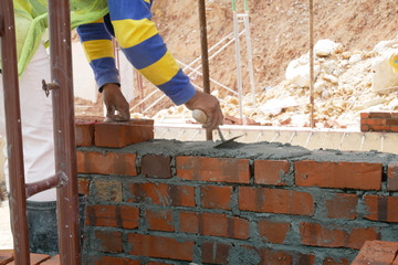 Brickwork by construction workers at the construction site. Workers laying the clay brick and stacked it together using mortar to form the wall. 