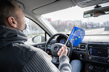 .Middle aged man in the medical mask with Germany flag driving a car. symbol of adverse epidemiological situation in countries. Coronavirus. Pandemic