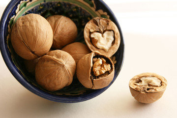 Walnuts in bowl on white background, top view with copyspace. 