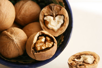 Walnuts in bowl on white background, top view with copyspace. 