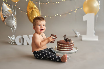 Smash cake party. Little cheerful birthday boy with first cake. Happy infant baby celebrating his...