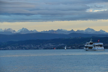 zurichsee with course boat and the alps in the evening mood