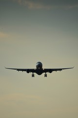 Silhouette of a plane landing in the summer with the setting sun