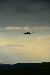 Naklejka na ściany i meble Silhouette of a landing plane in the evening sky
