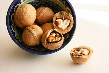 Walnuts in bowl on white background, top view with copyspace. 