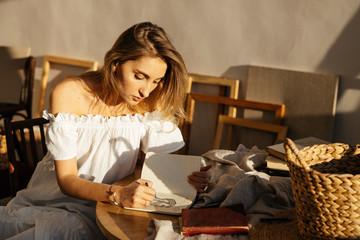 girl in a white dress draws at the table