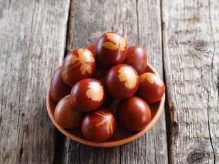 Easter. Colored eggs with a decoction from the onion skin. The traditional method of natural dyeing. Side view.Eggs on a plate on a wooden background.Space for text.