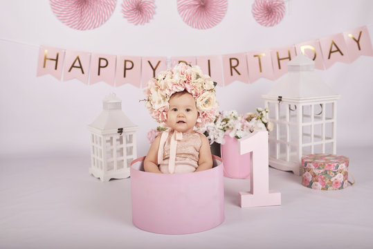 Smash cake party. Little cheerful birthday girl with first cake. Happy infant baby celebrating his first birthday. Decoration and photo zone for first year. One year baby celebration. Pink decor