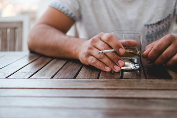 a man is holding a glass with a drink and a cigarette. pernicious habits. hazardous to health.