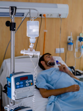 Teenage boy with a beard and wearing an oxygen mask, in a hospital room