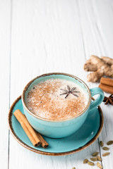 Masala tea in a ceramic cup with cardamom, star anise, cinnamon and ginger on a wooden background. Antiviral drink for immunity. Top view, place for text.