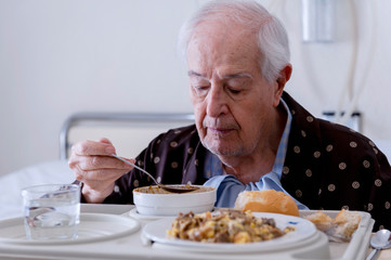 Elderly man hospitalized, eating in the room