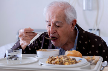 Elderly man hospitalized, eating in the room