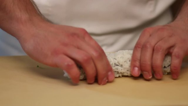 Chef's hands rolling a sushi roll. Sushi making process. Rolls the sushi roll