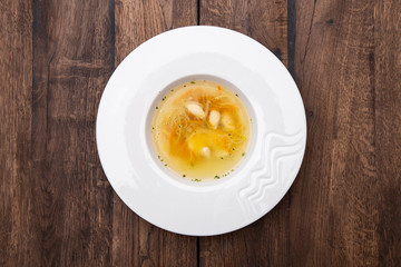 Chicken consomme with dumplings .
Chicken broth with chicken fillet dumplings and quail egg. Healthy dietary tasty food, homemade meals. A plate of  Chicken broth. Top view.