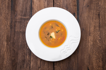 A plate of Minestrone soup in a white plate on a wooden table. Traditional Italian food, restaurant menu concept.