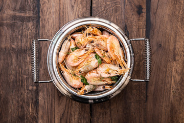 Shrimp fried in a frying pan on a wooden old table, top view