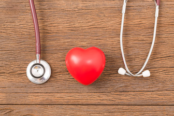 red heart with stethoscope on wooden table