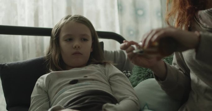 Mama podaje małej c&oacute;rce lekarstwo.