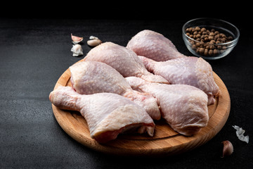 Raw chicken legs on black background.