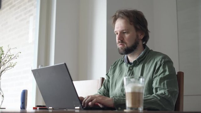 Mann im Homeoffice am Laptop in der Wohnung