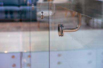 Stainless steel handrail support and glass wall in modern building. Selective focus.
