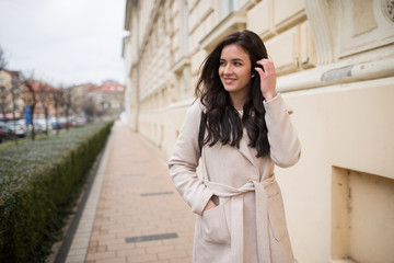 Fototapeta premium girl in a coat walks down the street and looks from the side
