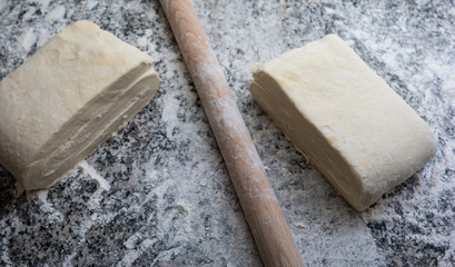 Raw folded homemade pastry dough on a marble kitchen counter top freshly made top view ready for chilling