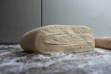 Raw folded homemade pastry dough on a marble kitchen counter top freshly made ready for chilling