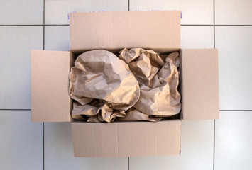  Opened box with goods covered with paper. Online store delivery unpacking.