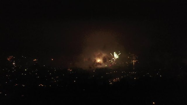 Aerial view of fireworks during newyears evening starting with a still and afterwards slowly turning
