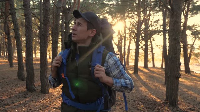 man tourist is walking lifestyle through the woods with a backpack on a hike. concept travel tourism adventure overcoming difficulties. male hiker walking go through the wild forest pine forest sunset
