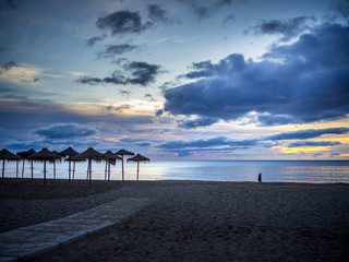 Fototapeta premium Lonely person walking on the beach at sunrise