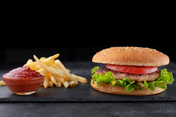 Hamburger with meat, potatoes and sauce, on a black background