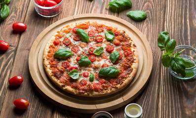 Delicious margherita pizza with tomatoes and basil on wood.