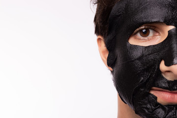 Black mask on man face, well groomed man getting spa treatment. Handsome young guy get Moisturizer rejuvenating black mask on facial skin for healthy facial skin. Beauty, Skin care concept copy space