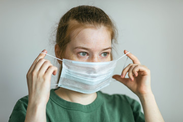 Woman puts on a protective medical mask. Prevention of infection and dissemination of coronavirus, quarantine