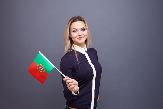Immigration and the study of foreign languages, concept. A young smiling woman with a Portugal flag in her hand.