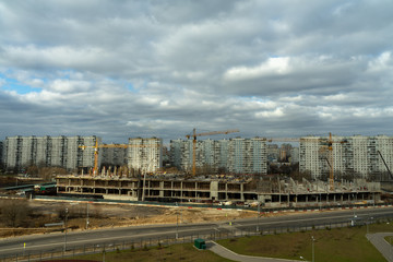 Fototapeta na wymiar aerial view of a residential area of ​​the city with gray volumetric clouds and a construction site