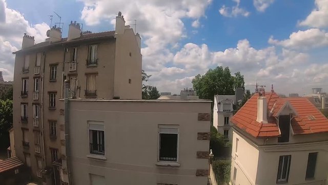 Paris commute train window, residential area on a partly cloudy day with a blue sky