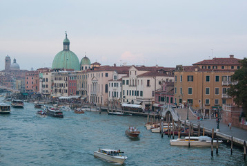 Twilight in Venice, Italy. View of the Grand Canal and houses on the shore, people ride boats.