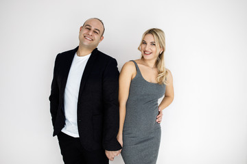 Young pretty blonde, expectant mother, stands next to her husband. Young couple, man and woman, beautifully and elegantly dressed, standing in studio on a white background. Pragnancy concept.