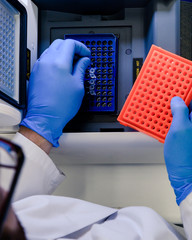Loading a DNA tube into a PCR (polymerase chain reaction) thermocycler machine in a bioscience...