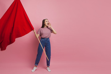 Young and beautiful girl with a red flag on a pink background. A socially active woman, to protest...