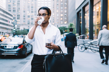 Ethnic formal woman drinking coffee in street