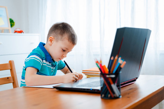 Distance learning online education. A schoolboy boy studies at home and does school homework. A home distance learning
