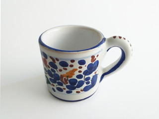 Aerial view of elegant painted ceramic mug with blue and grenade decorative elements on white background.