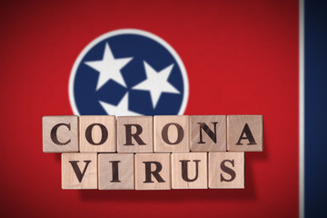 Flag of the state of Tennessee with wooden cubes spelling coronavirus on it. 2019 - 2020 Novel Coronavirus (2019-nCoV) concept, for an outbreak occurs in Tennessee, US.