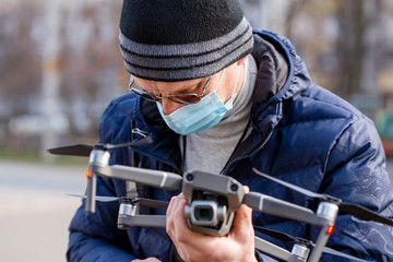 Obraz premium Surveyor in a protective mask prepares a quadcopter for flying around an object